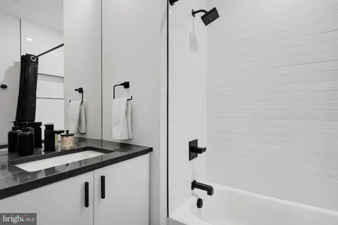 a bathroom with a granite countertop sink a mirror and shower