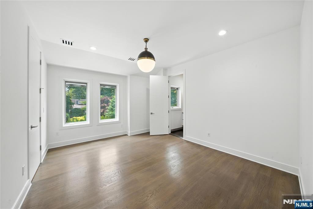 44 Floral Terrace Tenafly, NJ 07670 - Photo 22 of 49 an empty room with wooden floor chandelier fan and windows