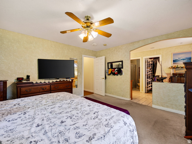 4380 Main Street Logan, UT 84321 - Photo 34 of 74 Primary bedroom with ceiling fan, integrated lighting, arched doorway, carpet flooring, tiled flooring, and a standard white door