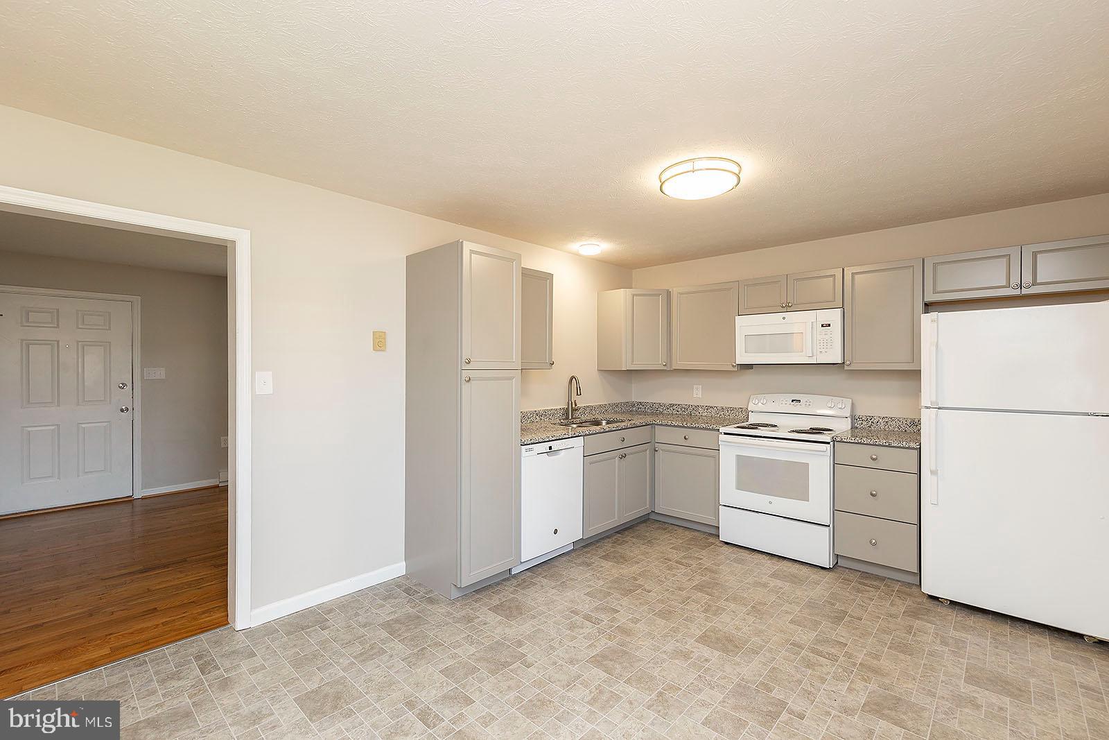 174 Double Church Road Stephens City, VA 22655 - Photo 7 of 29 a kitchen with a white stove refrigerator and white cabinets with wooden floor