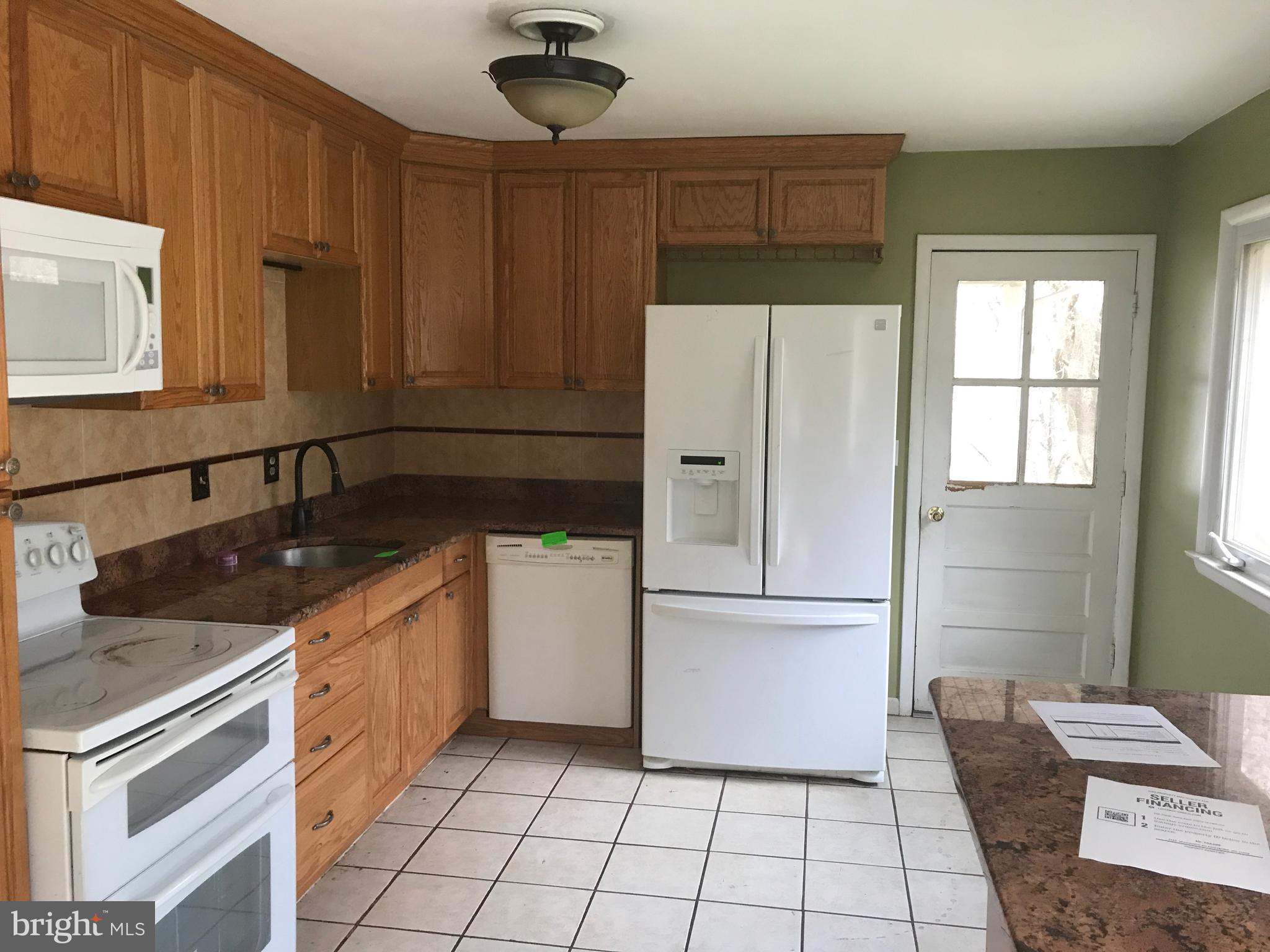 2117 Woodview Road Finksburg, MD 21048 - Photo 4 of 19 a kitchen with granite countertop a refrigerator a sink and white cabinets
