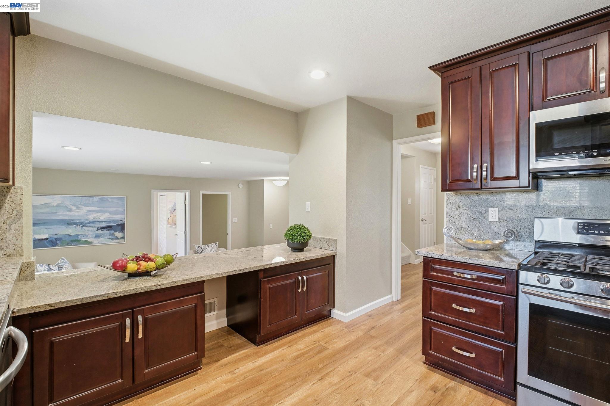 595 Seville Place Fremont, CA 94539 - Photo 11 of 43 a kitchen with stainless steel appliances kitchen island granite countertop a stove a sink and a microwave