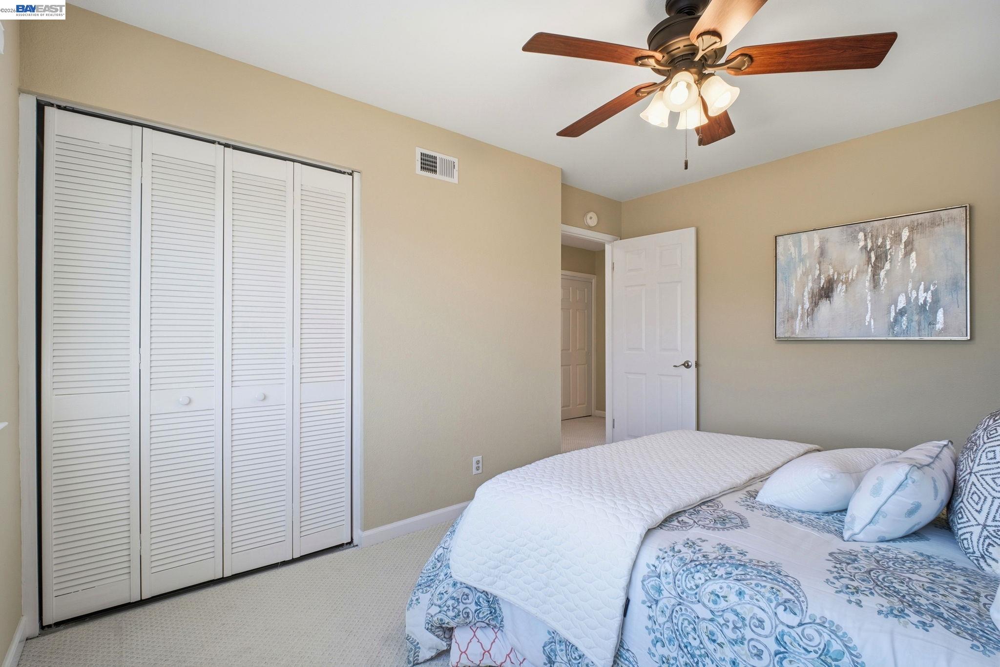 595 Seville Place Fremont, CA 94539 - Photo 20 of 43 a bedroom with a large bed and a chandelier fan