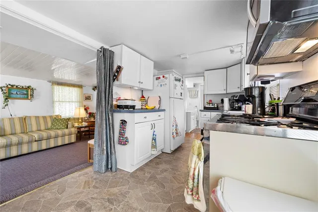 a kitchen with stainless steel appliances a stove a sink dishwasher a refrigerator and white cabinets with wooden floor