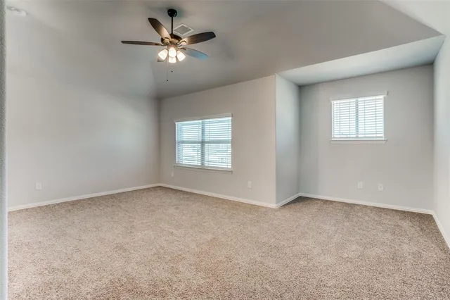 an empty room with windows and chandelier fan