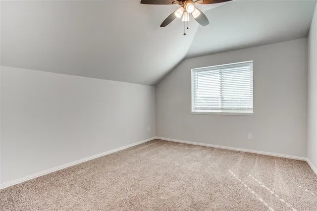 an empty room with a chandelier fan and windows