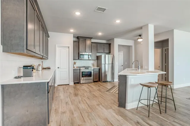 a kitchen with stainless steel appliances kitchen island granite countertop a refrigerator and a stove top oven
