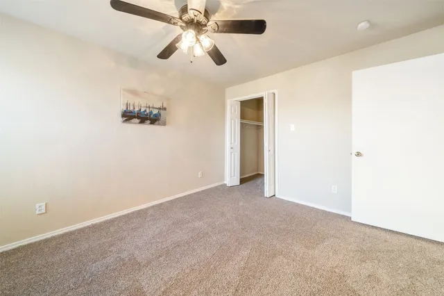 an empty room with closet and a ceiling fan