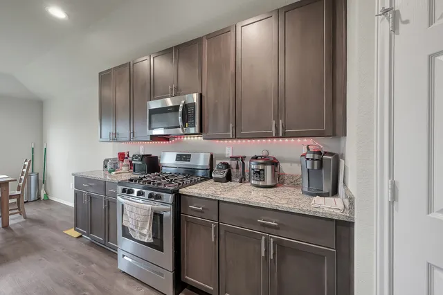 a kitchen with granite countertop stainless steel appliances a stove microwave and cabinets