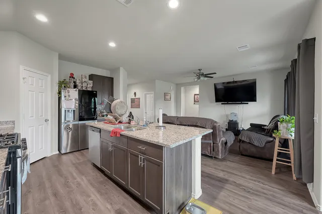 a living room with furniture a flat screen tv and a wooden floor