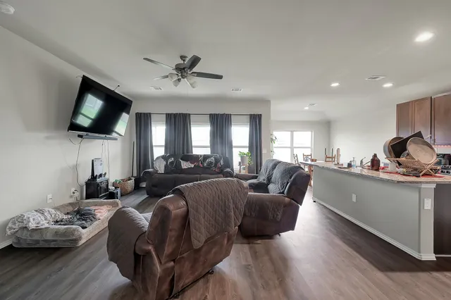 a living room with furniture a flat screen tv and kitchen view