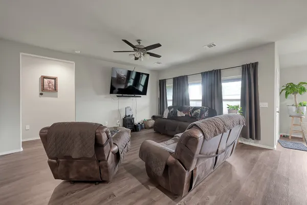 a living room with furniture a ceiling fan a flat screen tv and a window