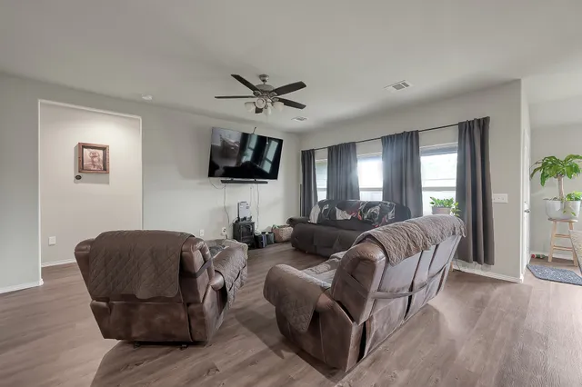 a living room with furniture a ceiling fan a flat screen tv and a window