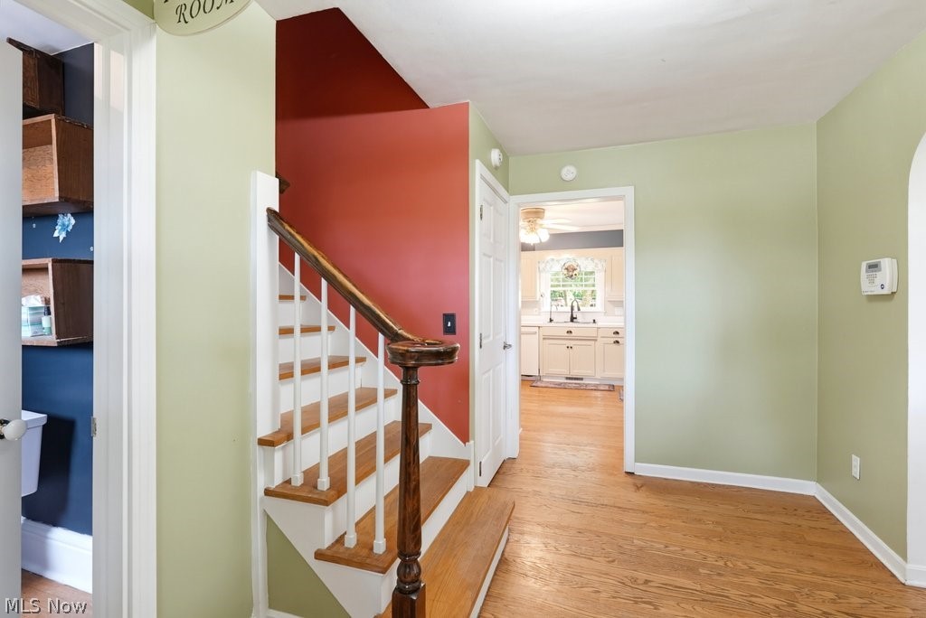 149 North Medina Line Road Akron, OH 44333 - Photo 5 of 42 Hardwood flooring throughout, a staircase with wood newel post and handrail, and an arched doorway leading to another space