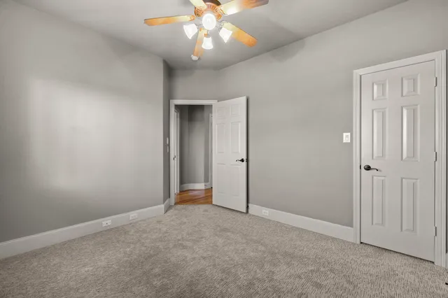 an empty room with closet and a chandelier fan