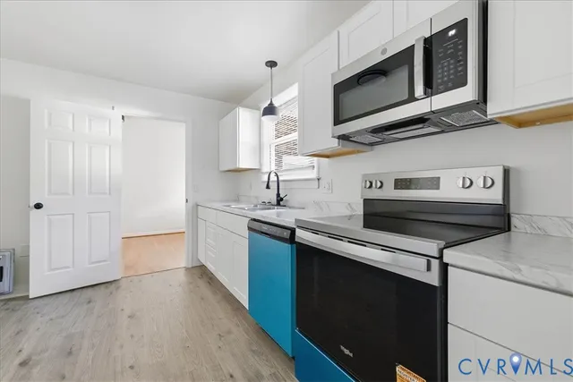 a kitchen with stainless steel appliances a sink cabinets and a wooden floor