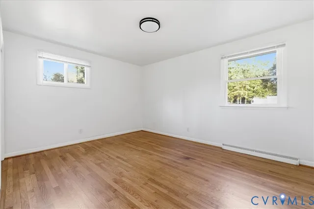 a view of an empty room with wooden floor and window