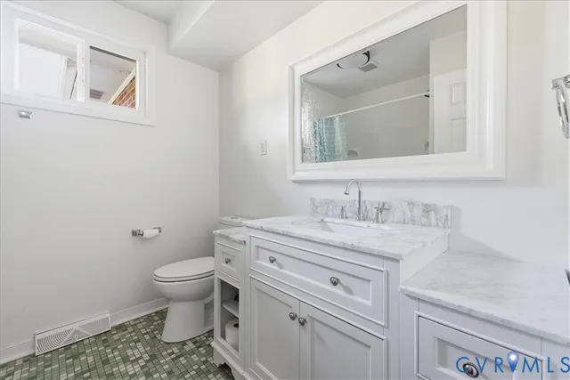 a bathroom with a granite countertop toilet sink and mirror