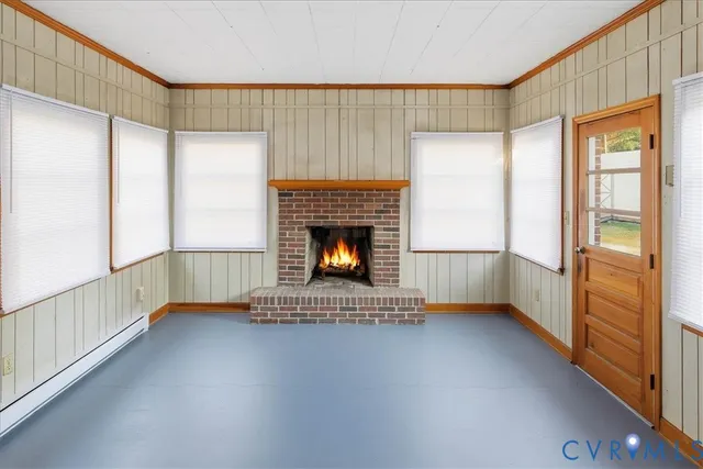 a view of an empty room with wooden floor fireplace and a window