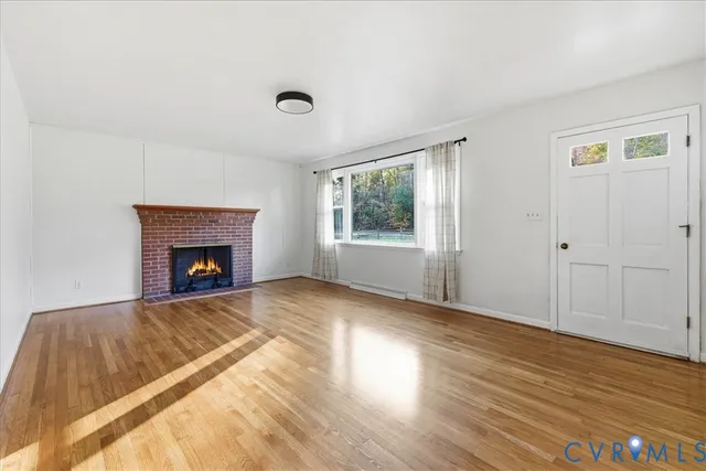 a view of empty room with wooden floor and fireplace