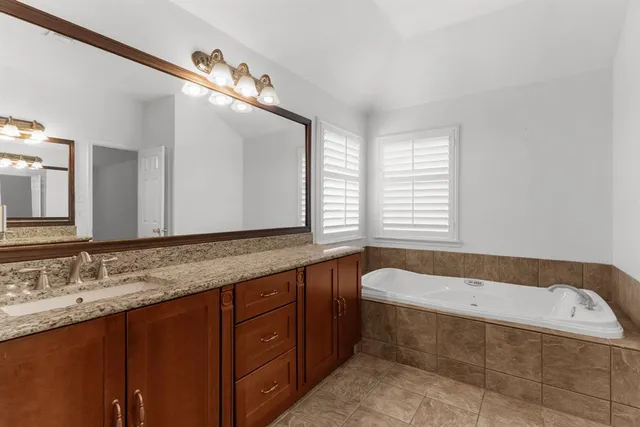 a bathroom with a granite countertop bathtub sink vanity and mirror
