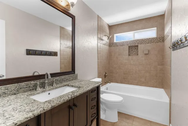 a bathroom with a granite countertop bathtub sink vanity mirror and toilet