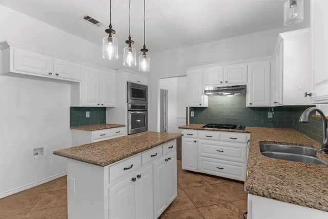 a kitchen with stainless steel appliances granite countertop a stove oven and a white cabinets