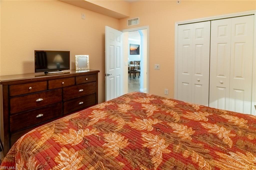 9723 Acqua Court, Unit 334 Naples, FL 34113 - Photo 13 of 49 a bedroom with a bed and a flat screen tv