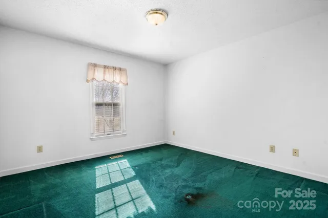 a view of an empty room with window and stairs