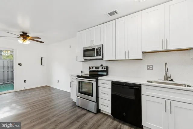 a kitchen with granite countertop a stove a sink and dishwasher with white cabinets