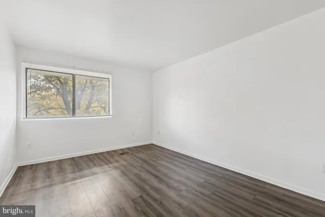 a view of an empty room with wooden floor and closet