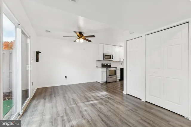 a view of kitchen with wooden floor electronic appliances and cabinets