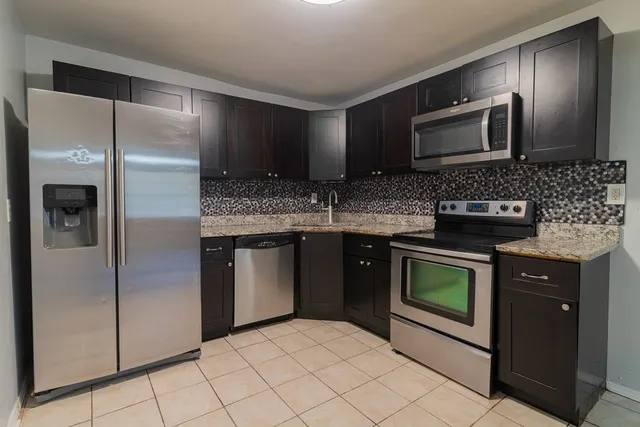 a kitchen with stainless steel appliances granite countertop a refrigerator and a stove top oven