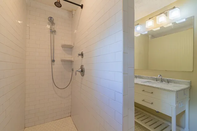 a bathroom with a granite countertop shower sink and mirror