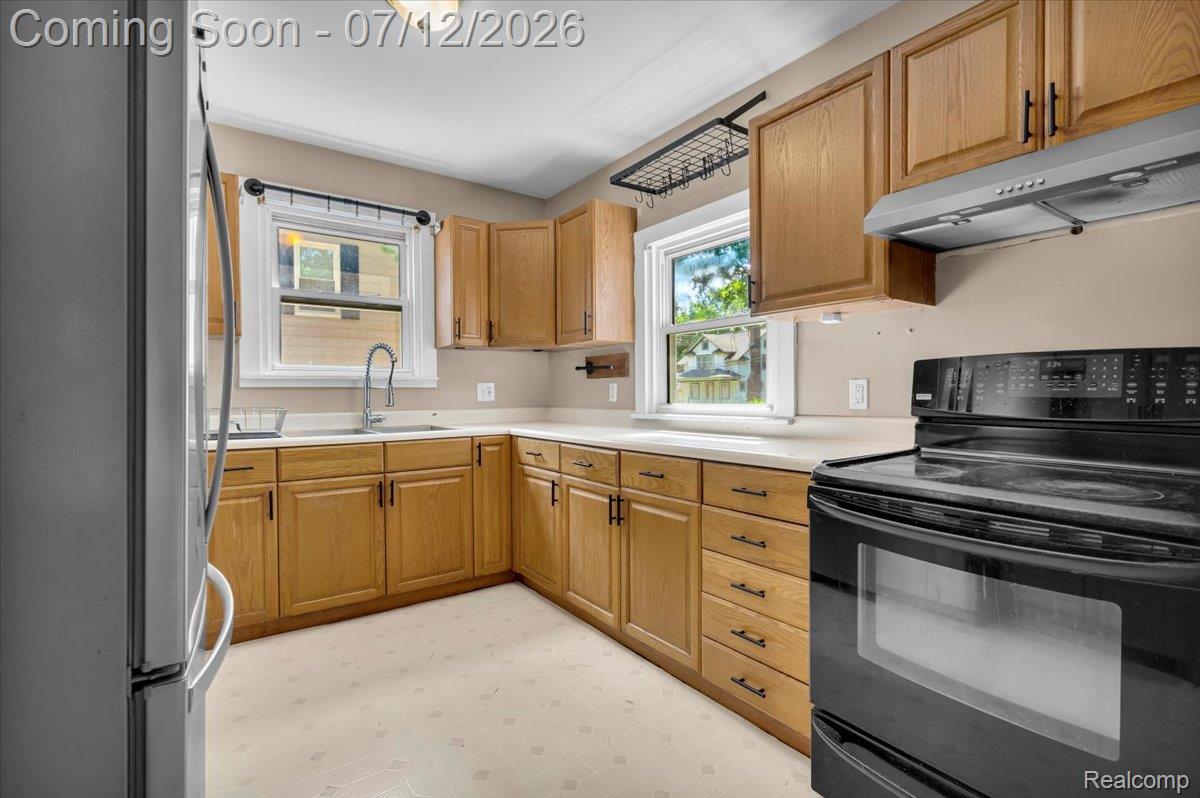 624 North Prospect Road Ypsilanti, MI 48198 - Photo 14 of 28 Kitchen featuring light wood cabinetry, light countertops, and a black electric range with an overhead range hood