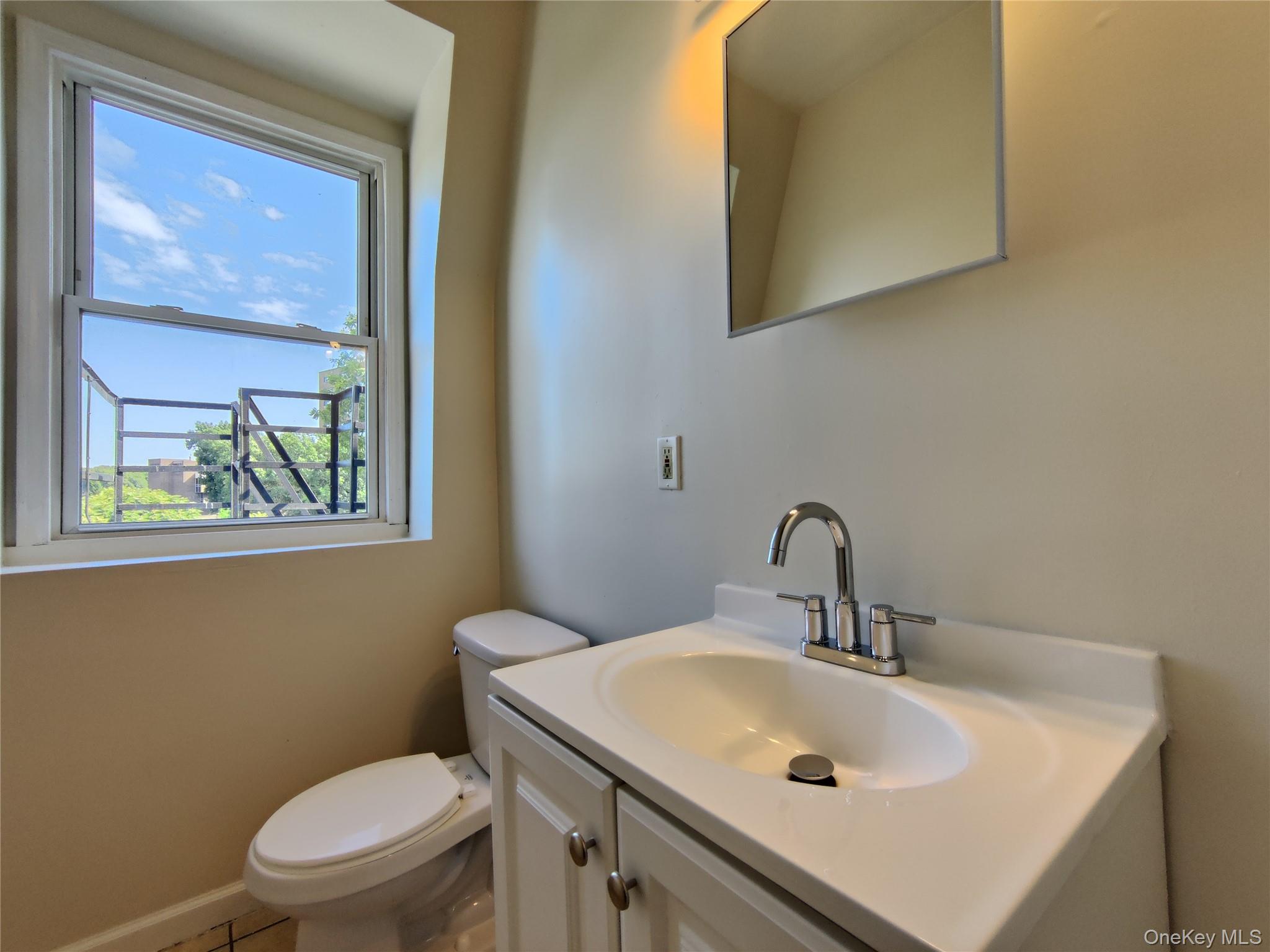 219 Mill Street, Unit 4 Poughkeepsie, NY 12601 - Photo 12 of 18 a bathroom with a sink a toilet and mirror