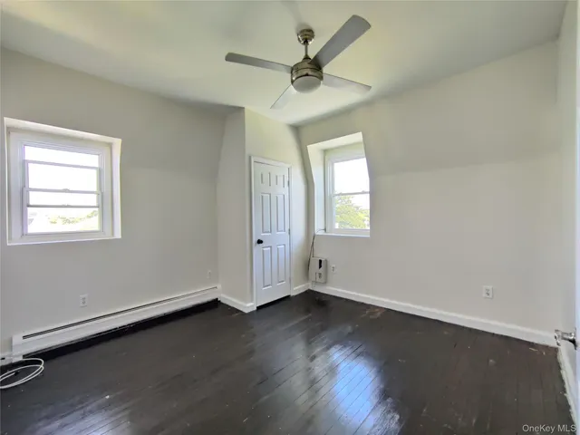 an empty room with wooden floor chandelier fan and windows