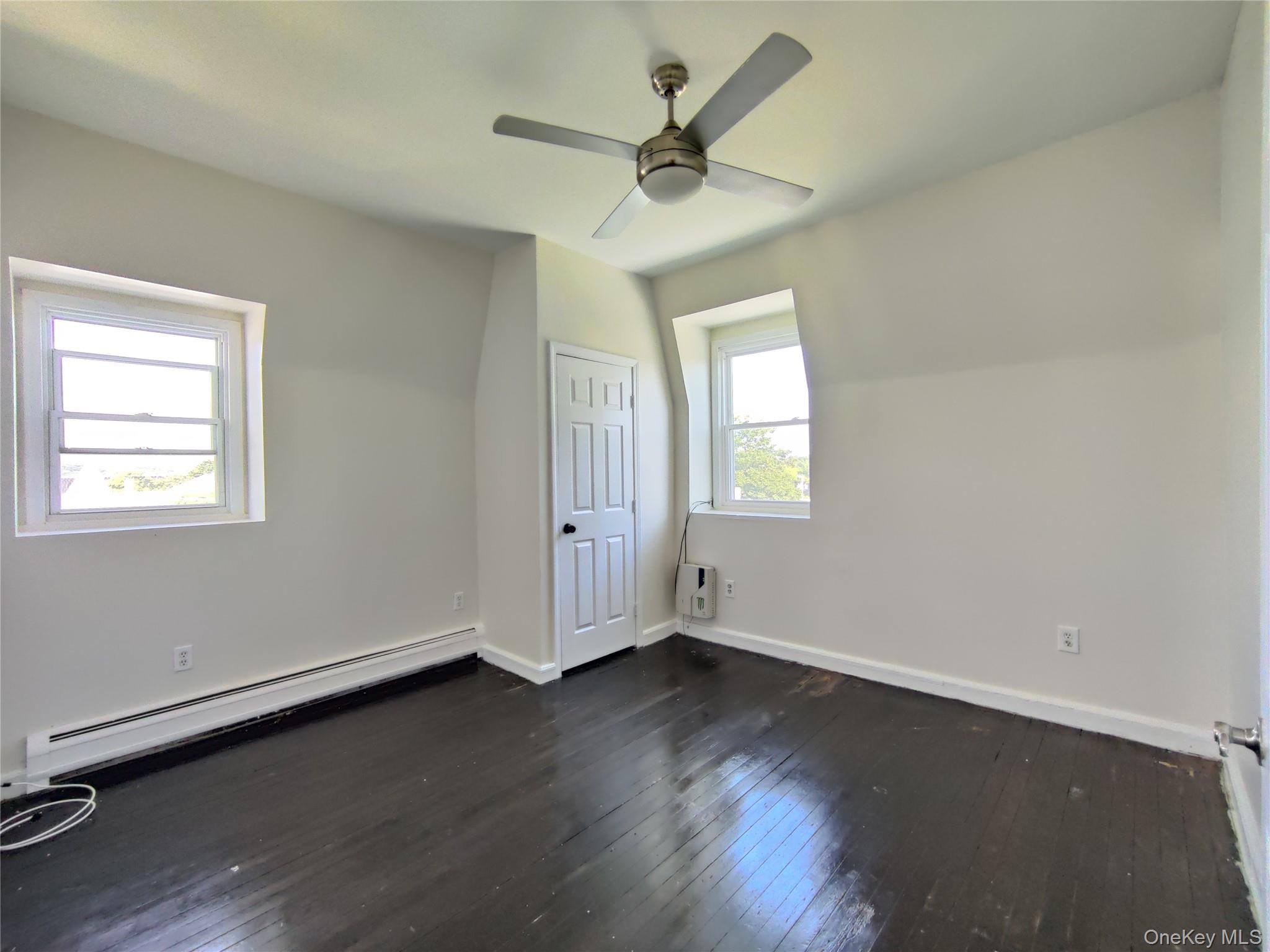 219 Mill Street, Unit 4 Poughkeepsie, NY 12601 - Photo 14 of 18 an empty room with wooden floor chandelier fan and windows
