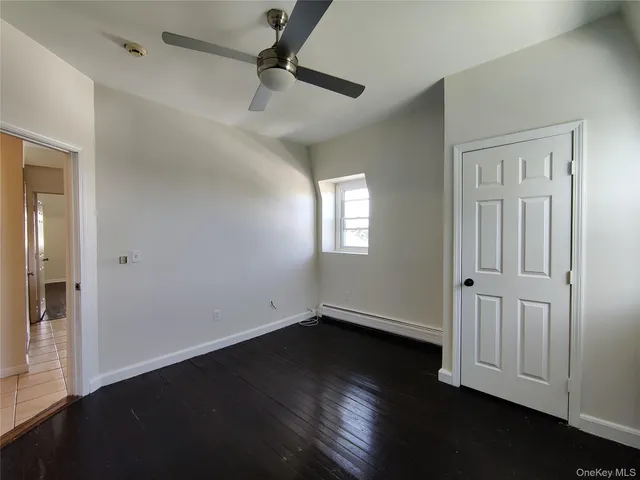 an empty room with wooden floor cabinet and windows