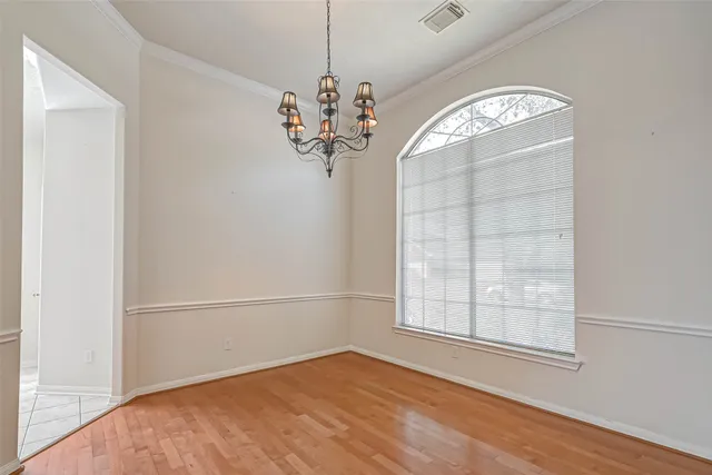 an empty room with wooden floor cabinet and windows