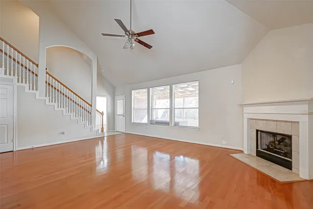 a view of an empty room with wooden floor fireplace and a window