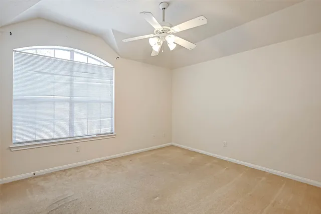 an empty room with a chandelier fan and windows