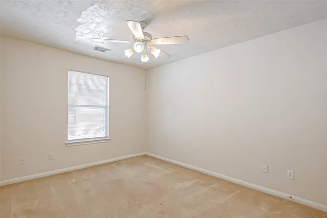 an empty room with a chandelier fan and windows