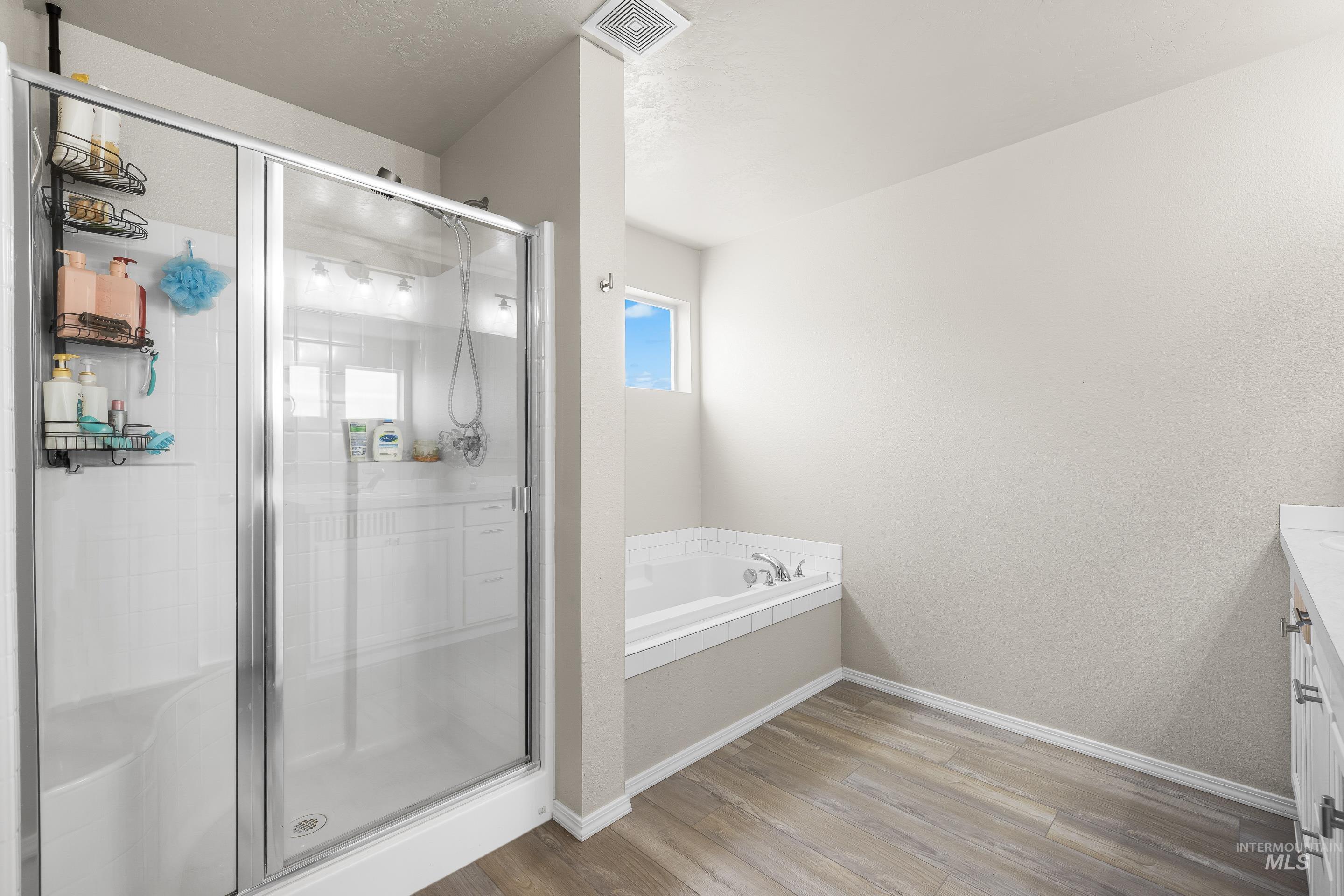 20202 Jennings Way Caldwell, ID 83605 - Photo 20 of 30 Full bathroom with vanity, light wood finished floors, a bath, and a stall shower