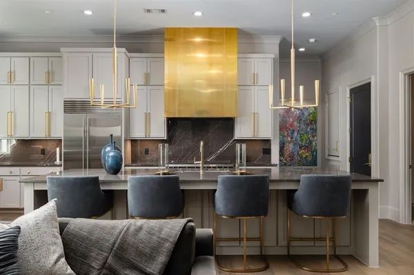 a kitchen with stainless steel appliances granite countertop a table chairs refrigerator and sink