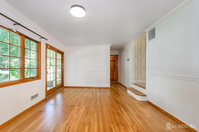 a view of an empty room with a window and wooden floor