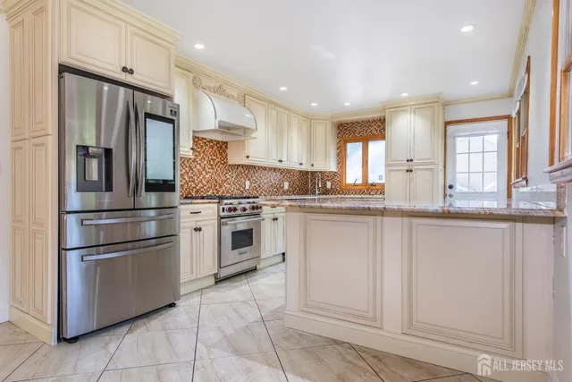 a kitchen with granite countertop white cabinets stainless steel appliances a sink and a window