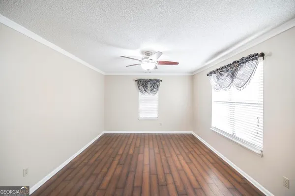 an empty room with a chandelier fan and windows