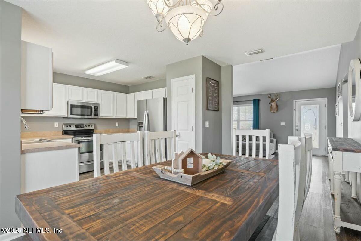 930 Red Fox Way Macclenny, FL 32063 - Photo 12 of 43 a kitchen with stainless steel appliances wooden floor dining table and chairs
