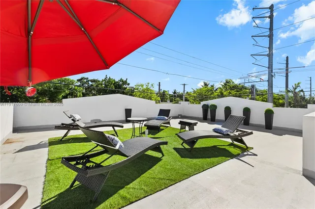 a view of a patio with chairs and a table under an umbrella